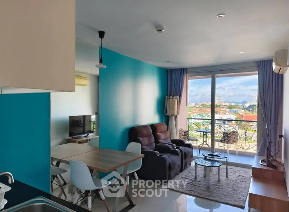 Modern living room with vibrant blue walls, cozy seating, and balcony offering stunning city views.