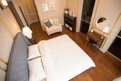 Elegant bedroom with plush bed, cozy seating, and stylish decor in a modern apartment.