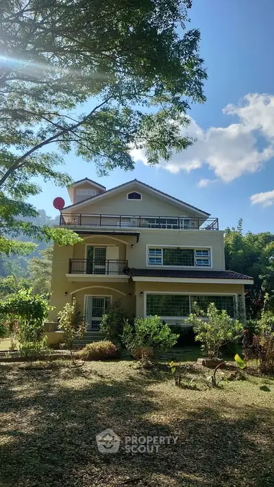 Charming multi-story house with lush garden and scenic mountain backdrop, perfect for serene living.