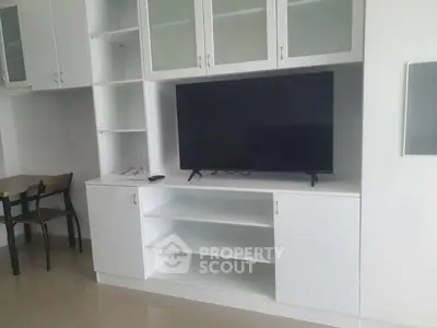 Modern living room with sleek white cabinetry and large flat-screen TV