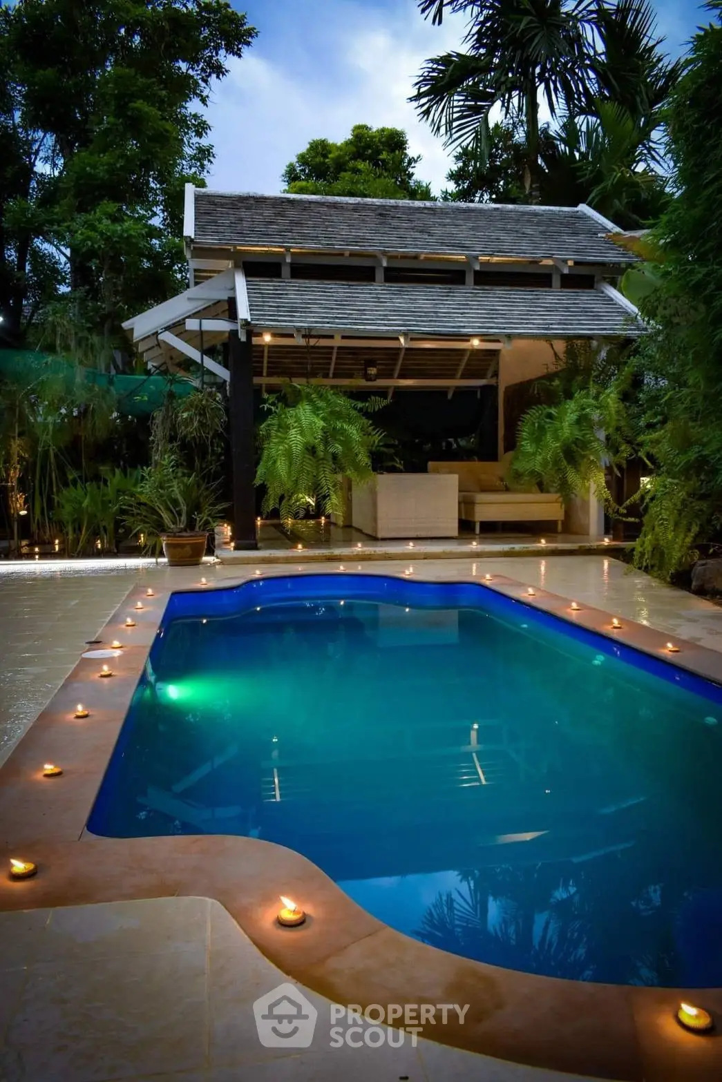 Luxurious outdoor pool with ambient lighting and lush greenery