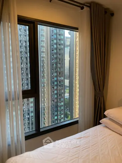 Luxurious bedroom with stunning city view from high-rise window, featuring elegant curtains and plush bedding.