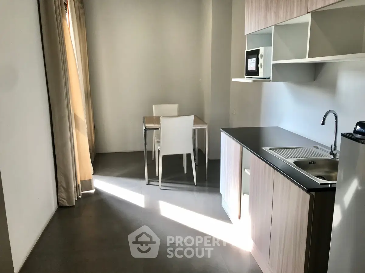 Modern kitchen with sleek cabinetry and dining area in a bright apartment