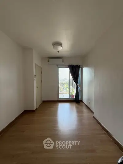 Spacious empty room with wooden flooring and balcony access, ideal for customization.