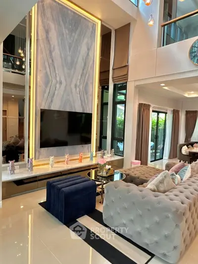 Luxurious modern living room with high ceilings, elegant decor, and large windows offering natural light.