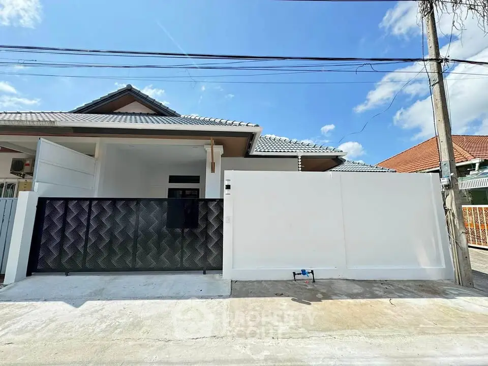 Modern single-story house with sleek design and gated entrance under a clear blue sky.