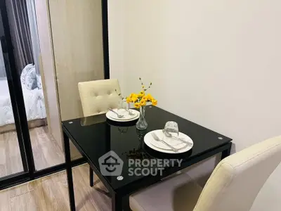 Modern dining area with elegant glass table and cozy seating in a stylish apartment.