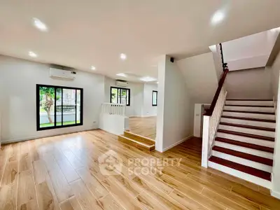 Spacious modern living room with wooden flooring and staircase in a bright home interior.