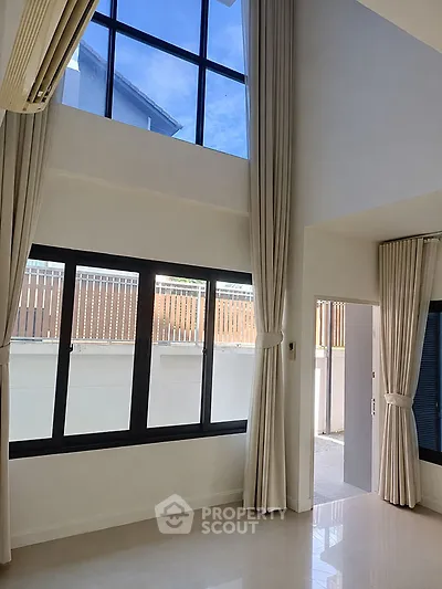 Spacious modern living room with high ceilings and large windows offering natural light.