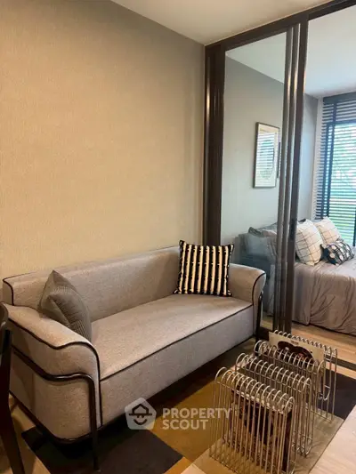 Modern living room with stylish sofa and glass partition leading to a cozy bedroom.