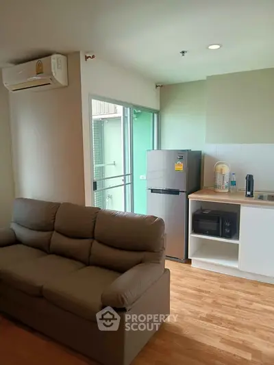 Modern living room with cozy sofa and sleek kitchen area in a bright apartment.