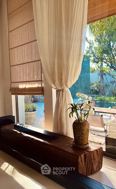 Elegant living room with large window, natural light, and garden view, featuring stylish decor and cozy ambiance.