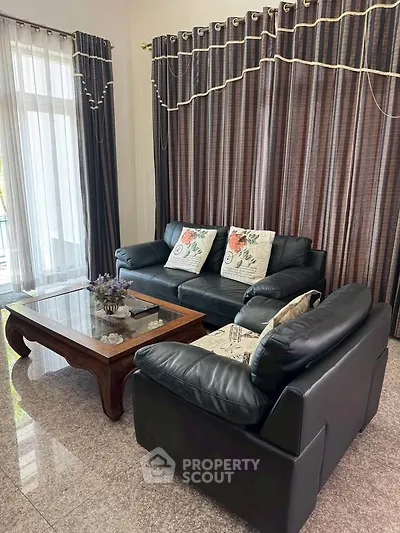 Elegant living room with black leather sofas and large windows for natural light.