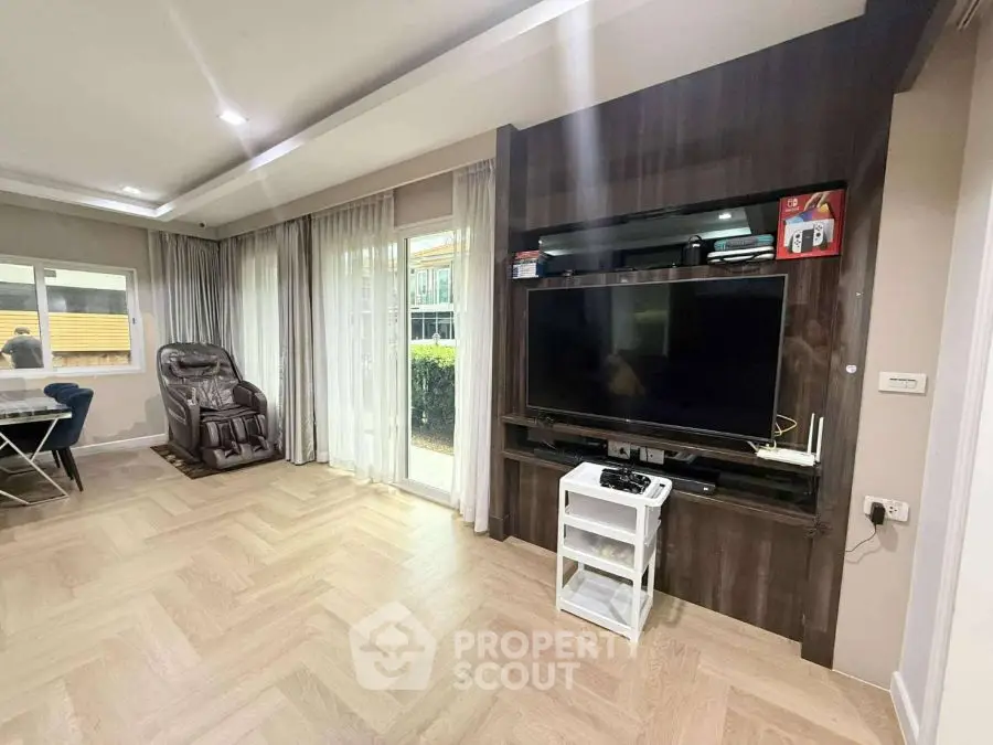 Spacious living room with modern entertainment center and large window view.