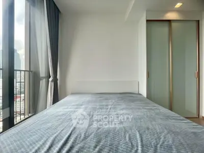 Modern bedroom with large window and city view, featuring sleek sliding closet doors.