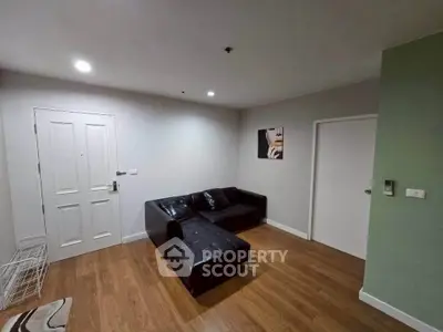 Modern living room with sleek black leather sofa and wooden flooring