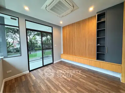 Modern living room with wooden accents and large windows overlooking greenery.
