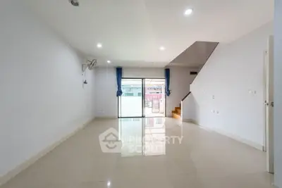 Spacious empty living room with large windows and staircase, ideal for customization.