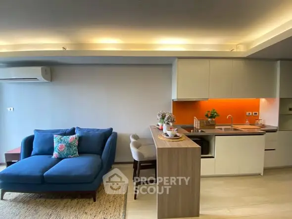 Modern open-layout living room with stylish kitchen and cozy blue sofa, perfect for urban living.