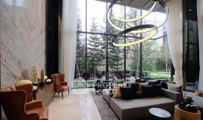 Luxurious modern living room with floor-to-ceiling windows and elegant decor overlooking a lush garden.