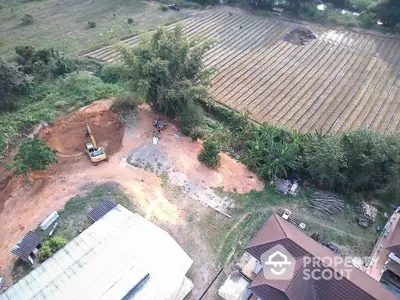 Aerial view of rural property with farmland and construction equipment, showcasing potential for development.