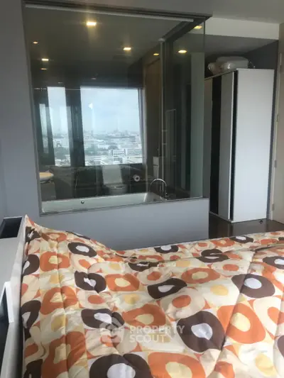 Modern bedroom with city view and glass-enclosed bathtub, featuring stylish decor and ample natural light.