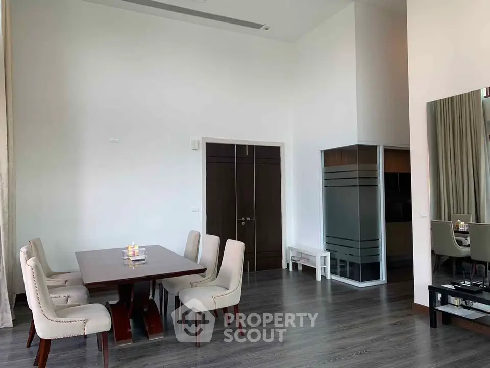 Spacious dining area with elegant table and chairs, high ceiling, and modern decor.
