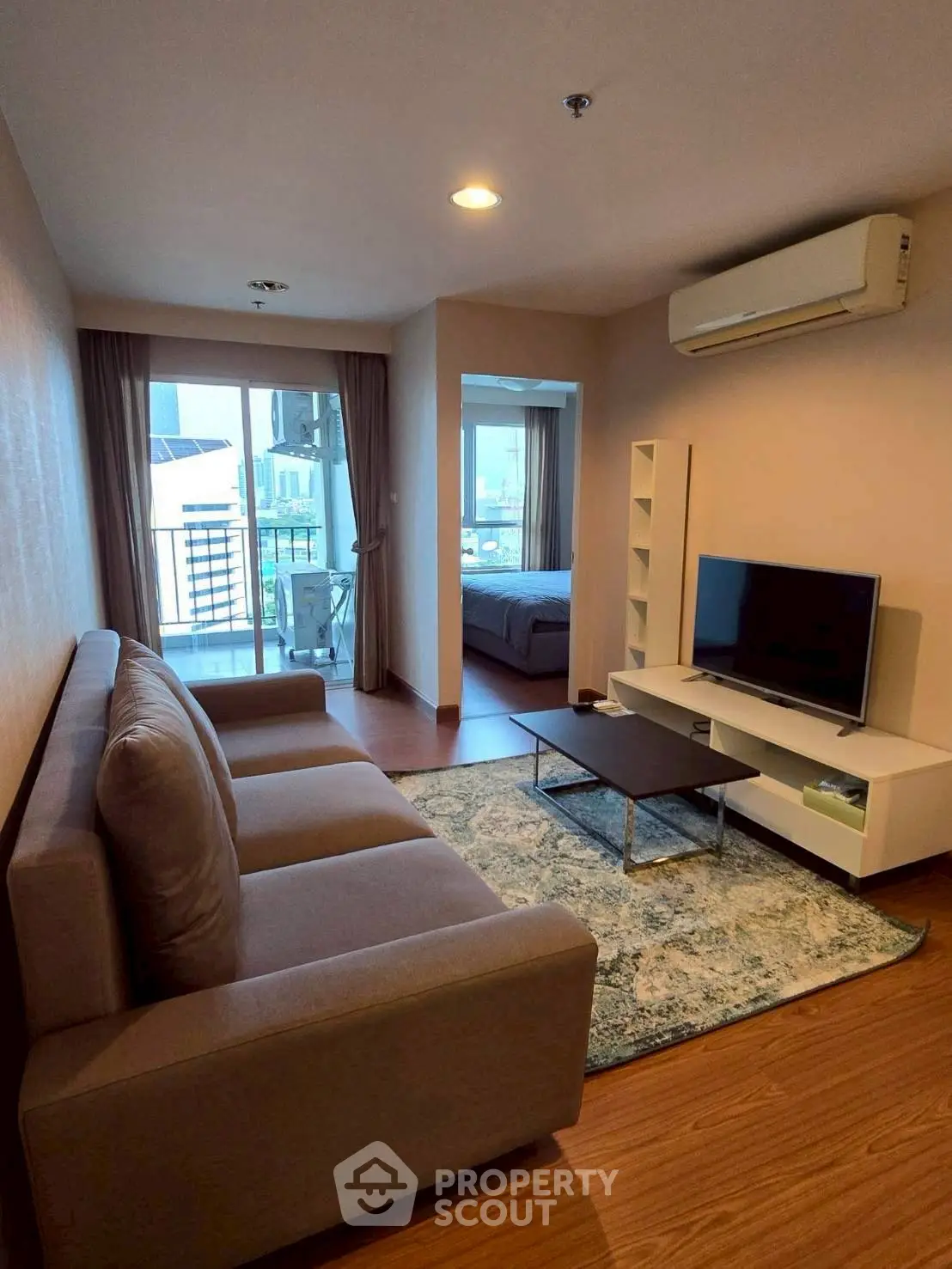 Modern living room with balcony view, featuring sleek furniture and air conditioning.