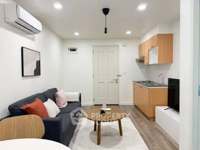 Modern living room with cozy sofa, stylish decor, and compact kitchen in open layout apartment.