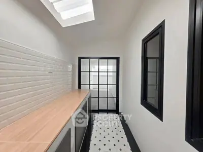 Modern kitchen with sleek black-framed glass door and stylish white tile backsplash.
