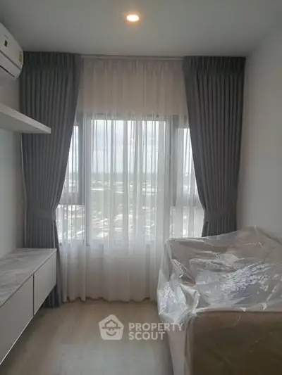 Cozy bedroom with large window and elegant curtains, offering a serene city view.