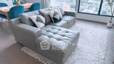 Modern living room with stylish leather sofa and city view from large window.