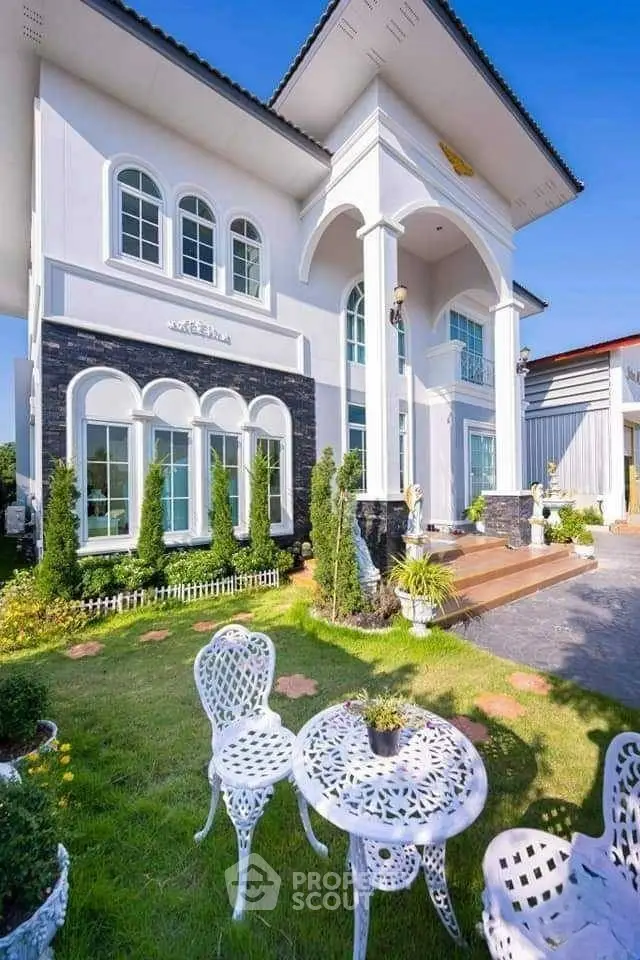 Stunning two-story house with elegant facade and charming garden seating area.