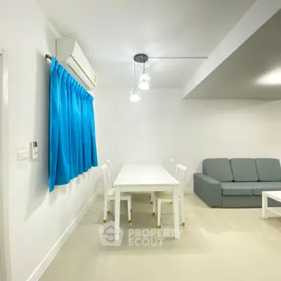 Modern living room with blue curtains and white furniture, featuring a cozy gray sofa.