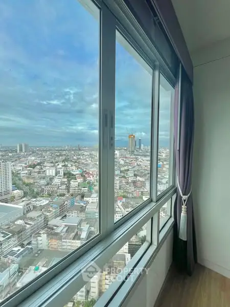 Stunning cityscape view from a high-rise apartment window with elegant curtains.