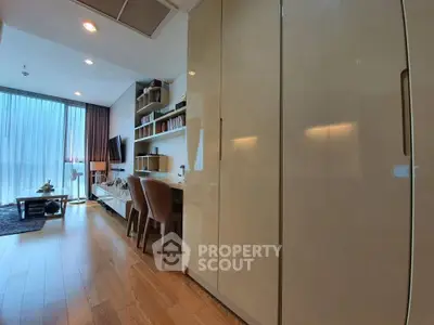Modern living room with wooden flooring, large windows, and built-in storage.