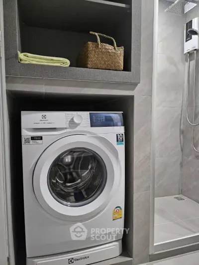 Modern bathroom with Electrolux washing machine and shower area, showcasing efficient use of space.