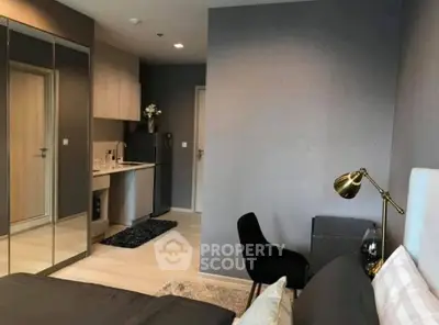 Modern bedroom with sleek design, mirrored closet, and compact kitchen area.