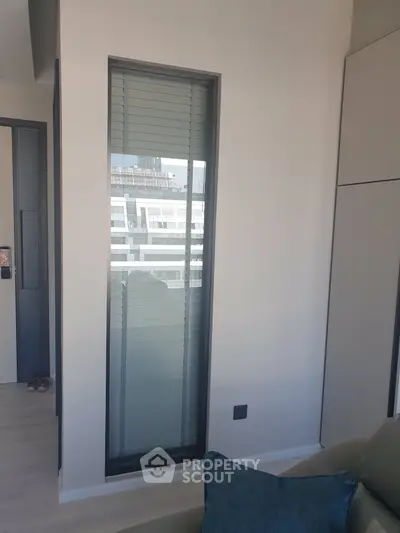 Modern apartment interior with large window and partial city view