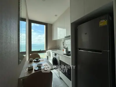 Modern kitchen with ocean view, featuring sleek appliances and dining area, perfect for culinary enthusiasts.