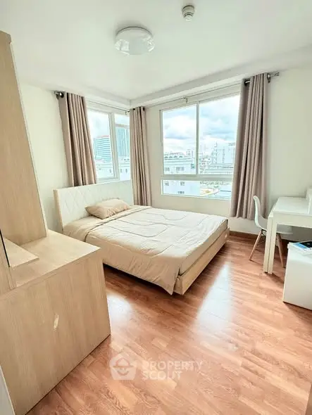 Bright and airy bedroom with large windows and modern furnishings in a high-rise apartment.