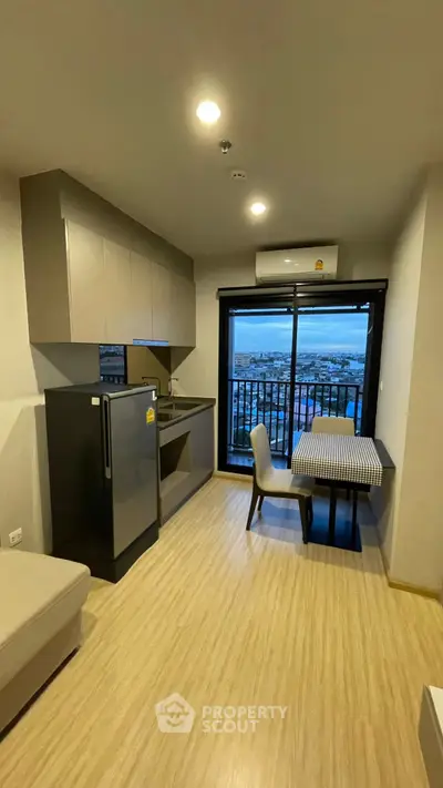 Modern compact kitchen with dining area and city view balcony.