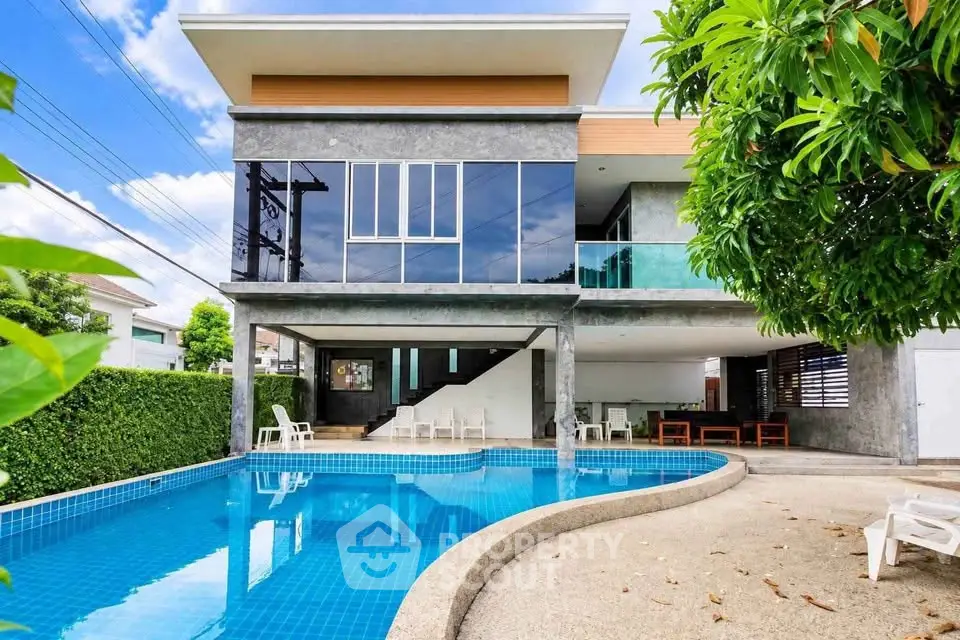 Modern luxury home with stunning pool and lush greenery, perfect for relaxation and entertainment.