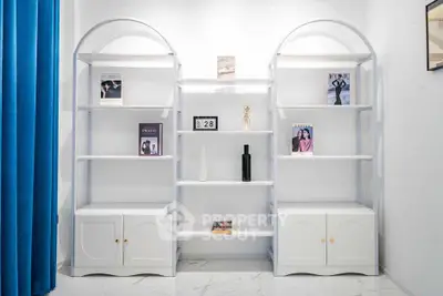 Modern minimalist living room with stylish white shelving and blue curtains.