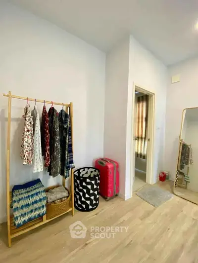 Spacious bedroom with wooden flooring and stylish clothes rack