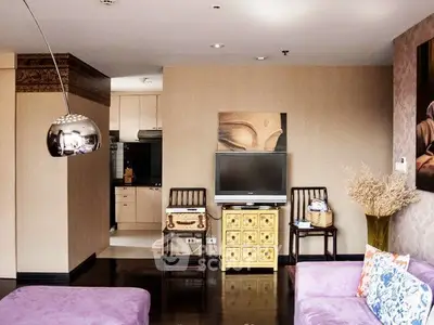 Chic living room with modern decor and open kitchen layout, featuring stylish furniture and elegant lighting.