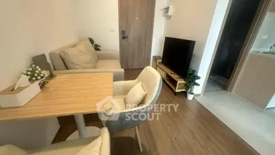 Modern living room with cozy seating and TV, featuring wooden flooring and stylish decor.