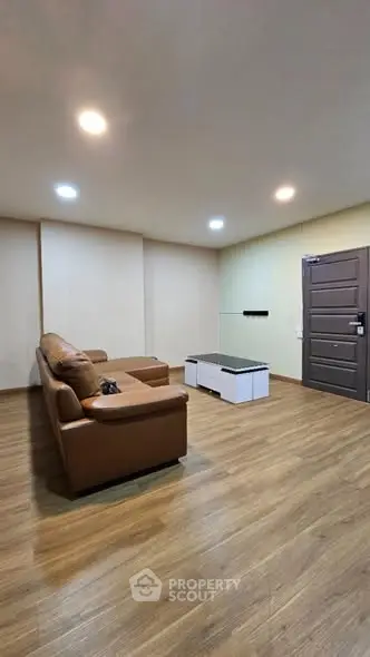 Spacious living room with modern leather sofa and wooden flooring