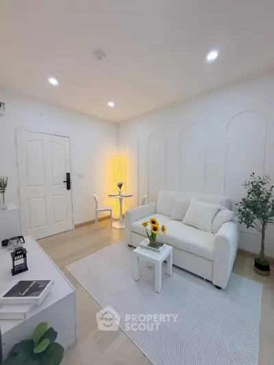 Bright and modern living room with white decor and cozy seating area, perfect for relaxation.