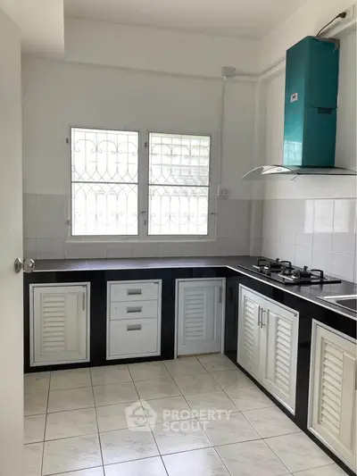 Spacious kitchen with modern gas stove and ample storage in a bright, airy setting.
